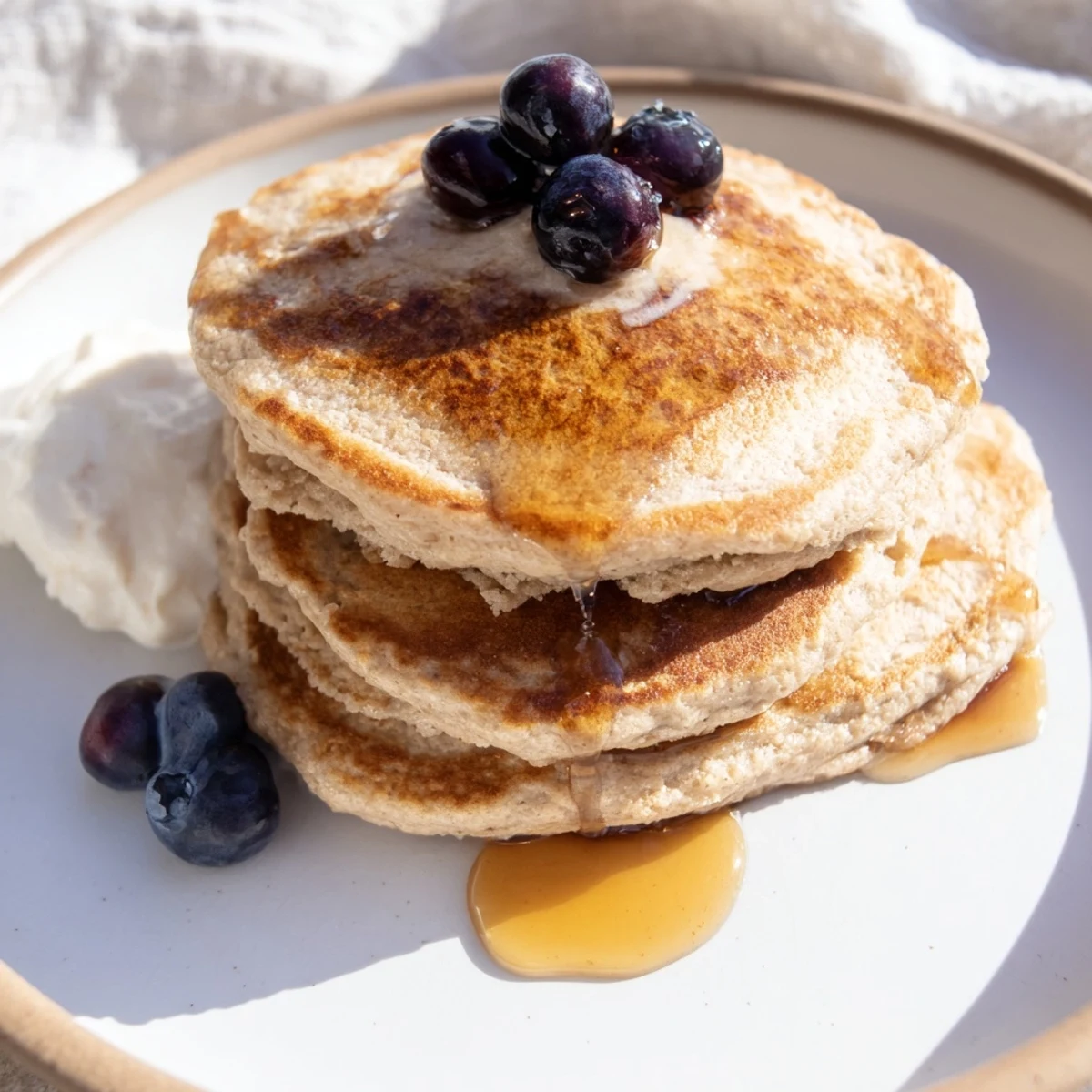 Stack of fluffy Protein Banana Pancakes, drizzled with maple syrup and fresh fruit for a delightful meal.