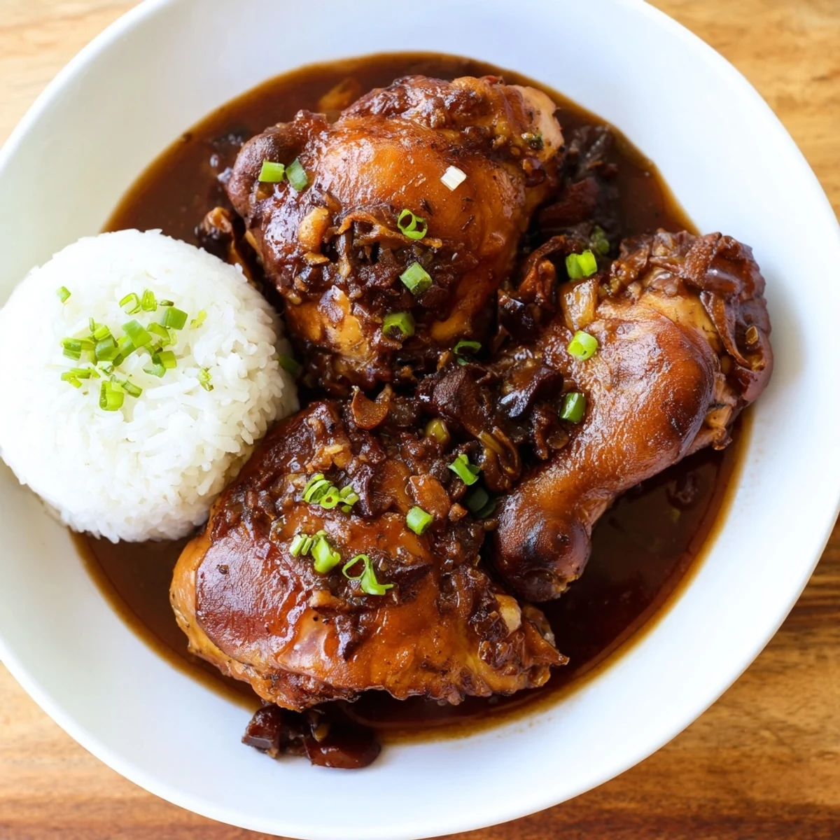 Steaming plate of Filipino Chicken Adobo with rice, garnished and ready for a delicious dinner.