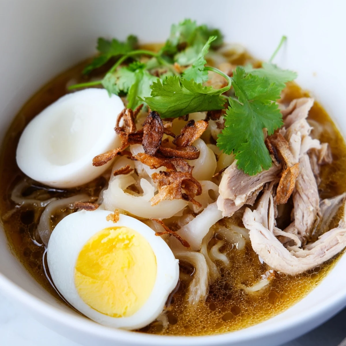 Spicy Thai Miso Ramen served with fresh noodles, sliced chicken, cilantro, chili, and rich golden soft-boiled eggs.