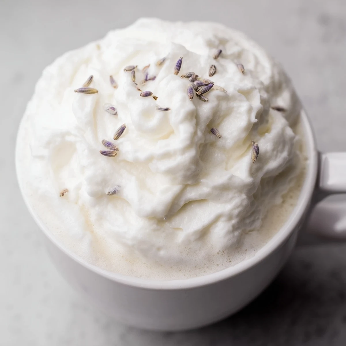 Steamed whole milk and homemade lavender syrup swirl together in a mug of creamy espresso, topped with fluffy foam and a hint of dried lavender garnish.