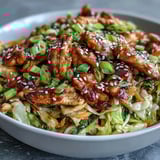 A close-up of Egg Roll Bowls with Chicken and Cabbage shows glossy soy-sesame sauce coating vegetables in a hearty low-carb dinner.