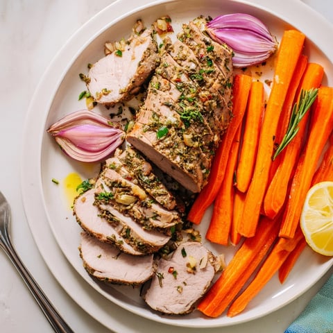 One-Pan Garlic Herb Pork Tenderloin and Carrots served fresh with roasted onions and parsley garnish.