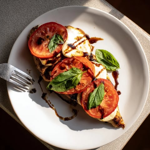 Golden brown Caprese Chicken Skillet topped with melted mozzarella, juicy tomato slices, and fresh basil leaves.