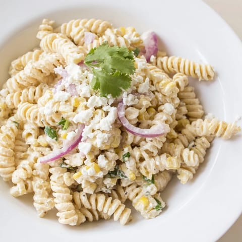 This delicious Creamy Street Corn Pasta Salad features crumbled cotija cheese and fresh cilantro garnishing.