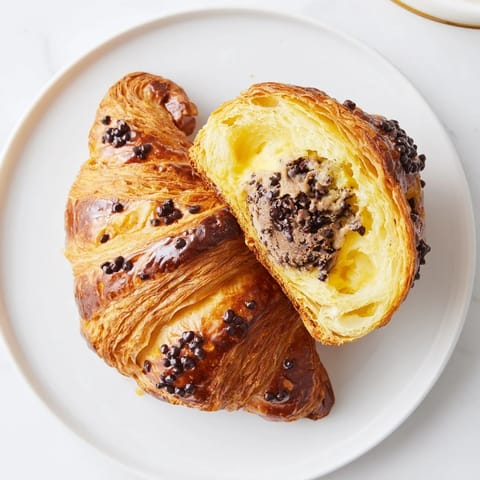 Warm, flaky Chocolate Cookie Croissants with a gooey chocolate chip cookie dough center, ready to eat.