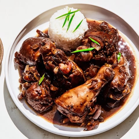A close-up of glistening Filipino Chicken Adobo, showcasing succulent chicken and a flavorful broth.