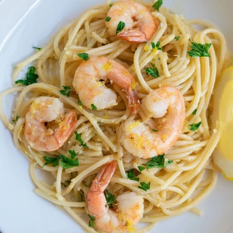 Close-up of vibrant Lemon Garlic Shrimp Pasta twirled on a fork, showing juicy shrimp, fresh parsley garnish, and a zesty, buttery coating.  