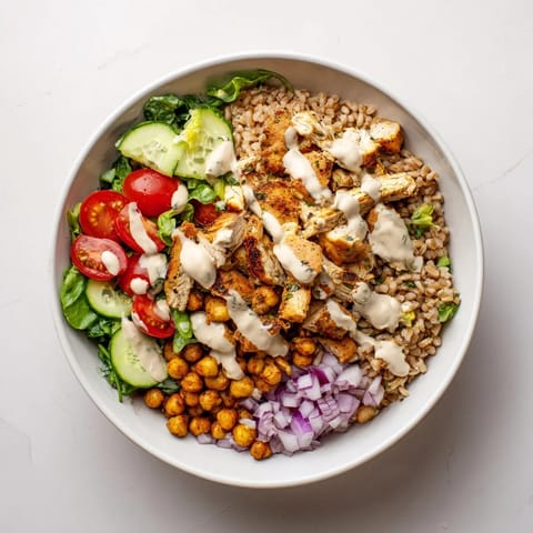 Golden roasted chicken slices and crispy chickpeas rest atop farro and greens, drenched in a creamy lemon-tahini sauce.