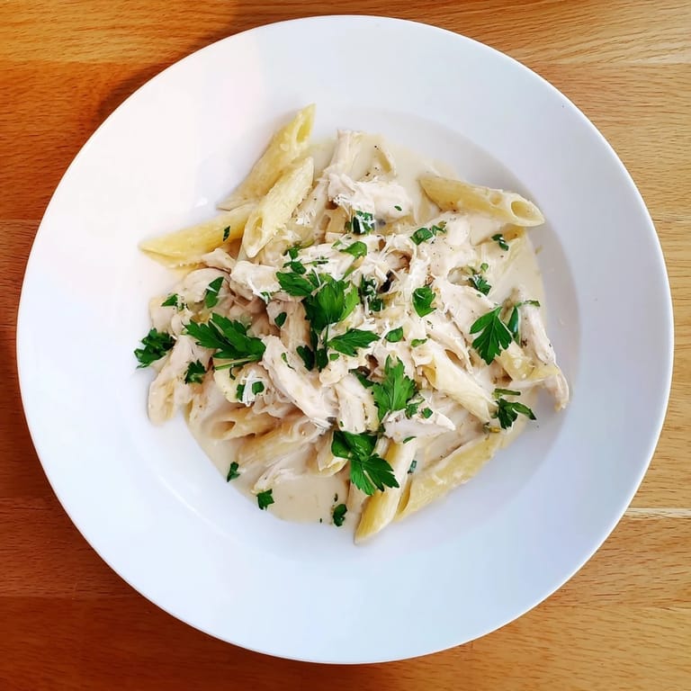 A close-up of Roasted Garlic Chicken Penne showing tender chicken slices and silky garlic cream sauce clinging to each pasta piece.