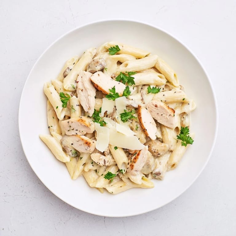 Serving suggestion for Roasted Garlic Chicken Penne: steaming pasta dish ready to enjoy, paired with a glass of crisp white wine.