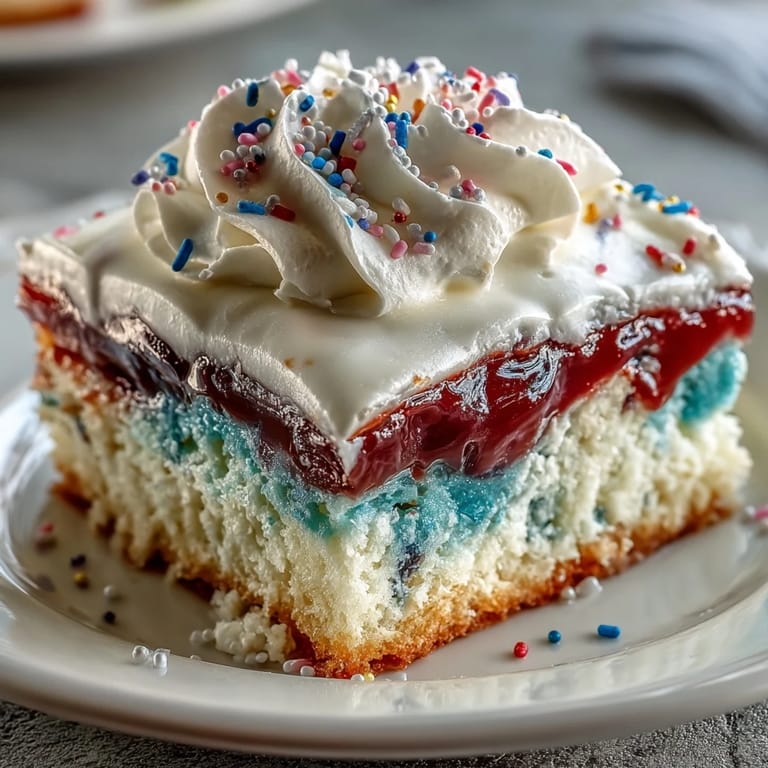 Layered Patriotic Poke Cake invitingly topped with smooth white chocolate ganache and fresh berries.