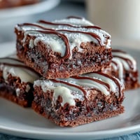 Baseball-themed brownie bites with white icing laces, perfect for game day desserts or sports party snacks.