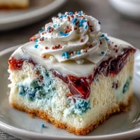 Festive Patriotic Poke Cake with white chocolate ganache, bursting with colorful gelatin.